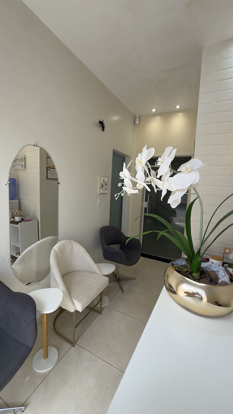 Sala de espera com espelho em arco, poltronas brancas e orquídea