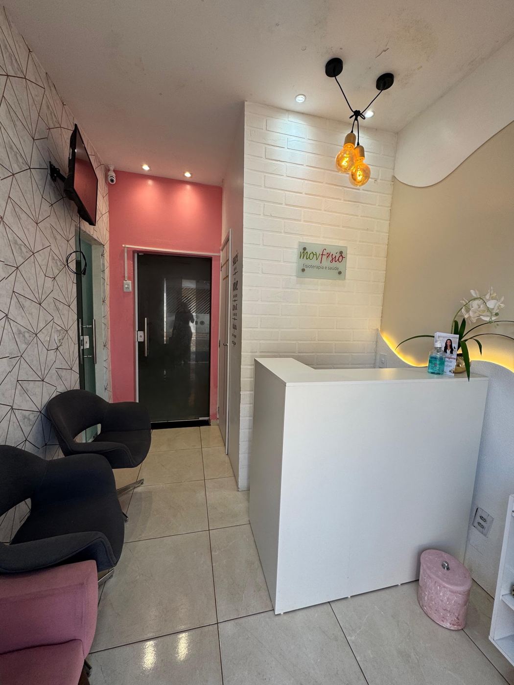 Corredor e recepção com parede rosa e detalhes em dourado